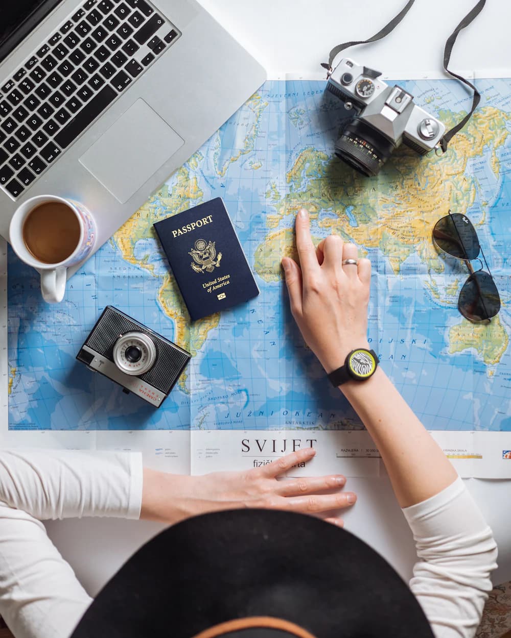 Planejamento de viagem sobre um mapa-múndi, com passaporte, câmera e laptop