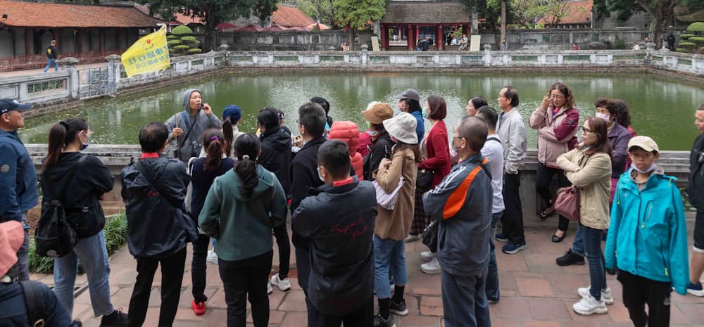 Grupo de turistas ouvindo um guia à beira de um lago